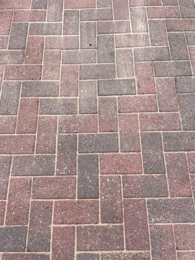 Patterned brick pavement featuring shades of brown and red in a herringbone layout.